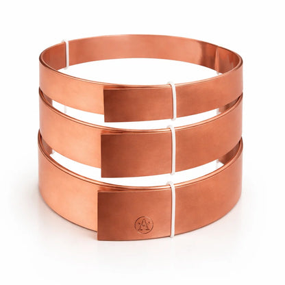 Four pure copper Vastu strip coils stacked to show the flat metal profile