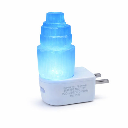 Selenite tower lamp illuminated blue on its white USB base against a clean background