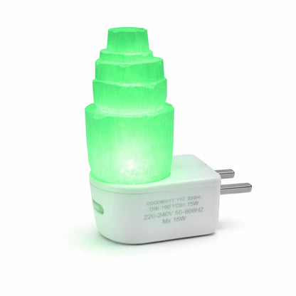 Selenite tower lamp illuminated green on its white USB base against a clean background