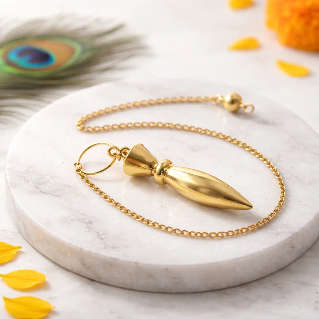 Heavy brass bullet dowsing pendulum with chain on a white marble plate