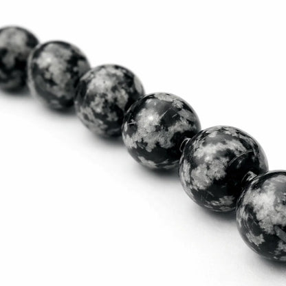 Natural snowflake obsidian crystal bracelet displayed in a softly lit product setting