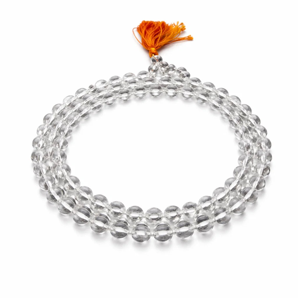 Full clear sphatik crystal mala arranged in a circle with an orange tassel on white
