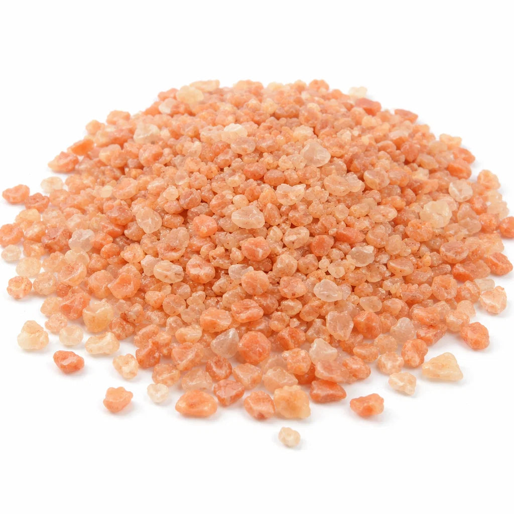 Pile of peach-coloured raw sunstone chips isolated on a clean white background