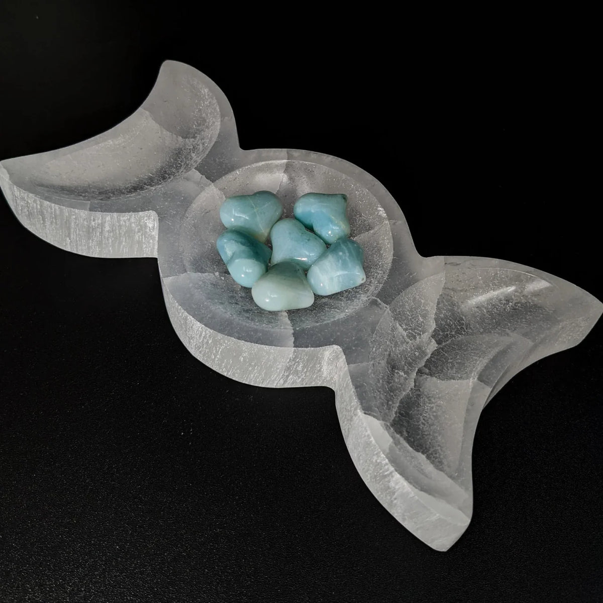 Triple moon selenite charging bowl shown in a close atmospheric product view