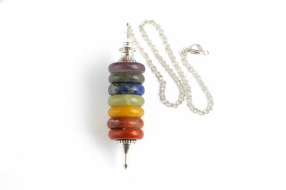 Seven chakra pendulum hanging from its silver chain on a white background
