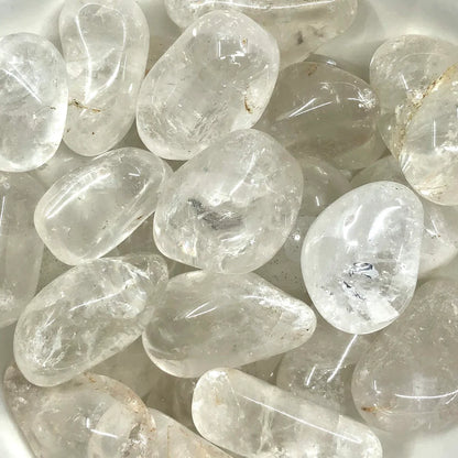 Macro view of clear quartz tumbled stones showing polished surfaces, colour variation and natural markings